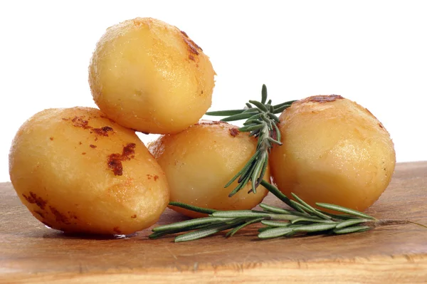 Жареный картофель с розмарином на деревянной доске — стоковое фото
