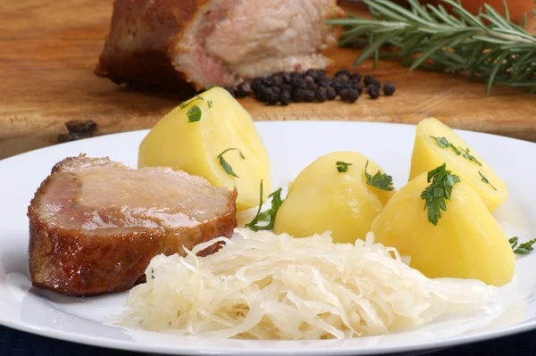 Geroosterd varkensvlees met gekookte aardappelen en zuurkool — Stockfoto