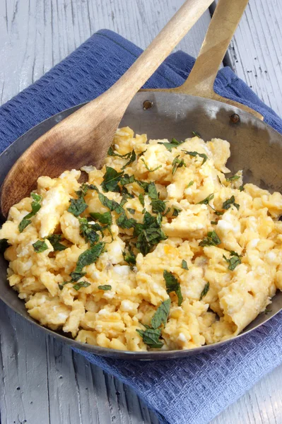 Scrambled eggs in a brass pan with chopped mint — Stock Photo, Image