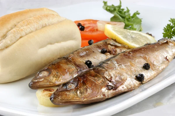 Grilované sardinky s chlebem a rajčaty na talíři — Stock fotografie