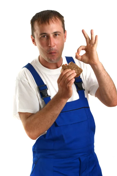 年轻工匠用蓝色整体吃火腿三明治 — 图库照片