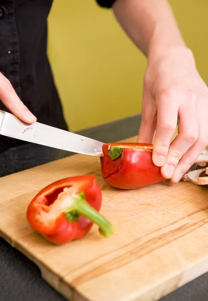 Fêmea cortando uma pimenta vermelha — Fotografia de Stock