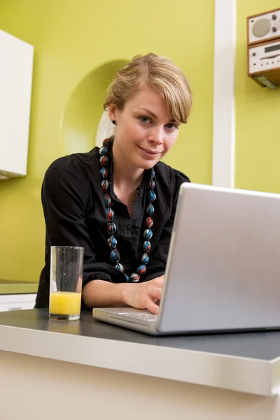 Kvinna använder dator i köket — Stockfoto