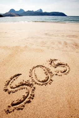 S.O.S written in the sand of an island with the ocean in the distance clipart