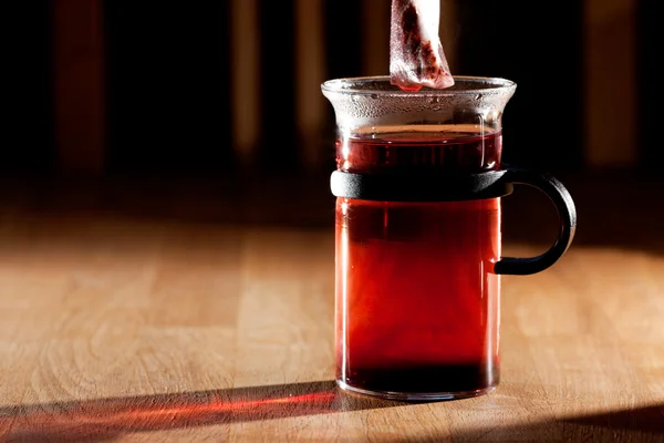 Un sachet de thé dans une tasse d'eau chaude avec une forte lumière du matin directionnelle — Photo
