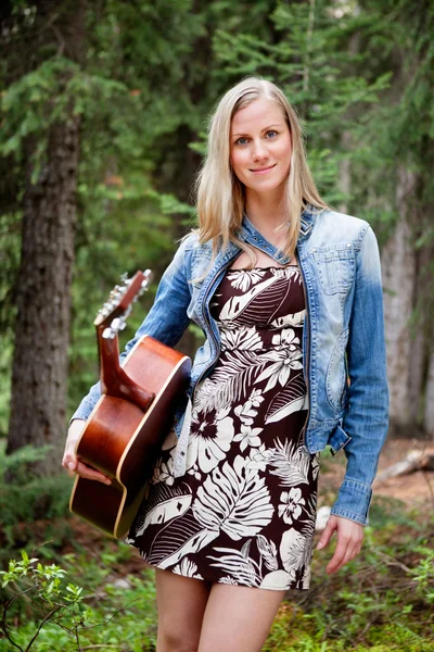 Vrouwelijke bedrijf gitaar tegen bomen — Stockfoto