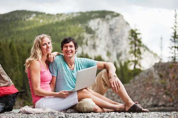 Avslappnad par med laptop medan camping — Stockfoto