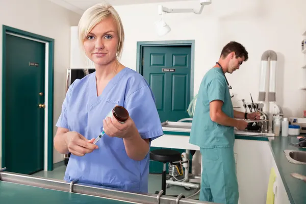 Enfermeira com seringa enquanto o médico escreve o relatório — Fotografia de Stock
