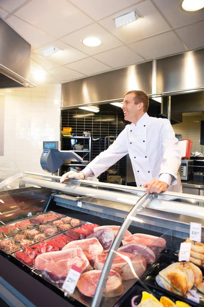 Cheerful chef on the counter of frozen meat — Stock Photo, Image