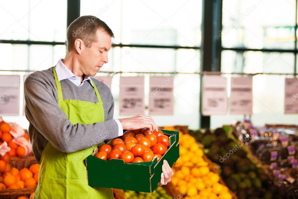 Market assistant holding box of tomatoes