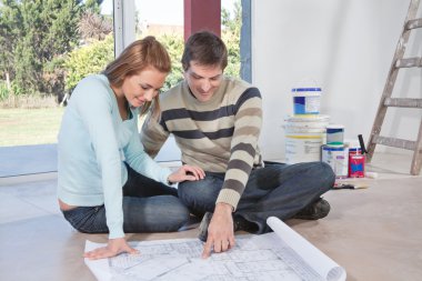 Man showing blueprint of their new house to his wife