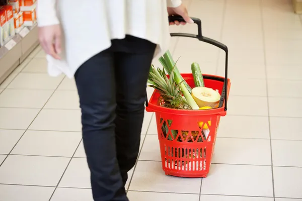 Mujer en supermercado tirando de la cesta — Foto de Stock