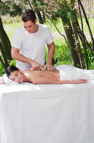 Hombre dando masaje a la mujer por un masajeador de madera — Foto de Stock