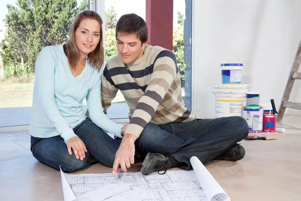 Couple assis sur le sol avec le plan de leur nouvelle maison — Photo