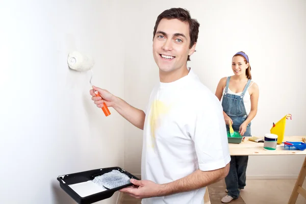 Uomo sorridente che dipinge il muro del suo nuovo appartamento — Foto Stock