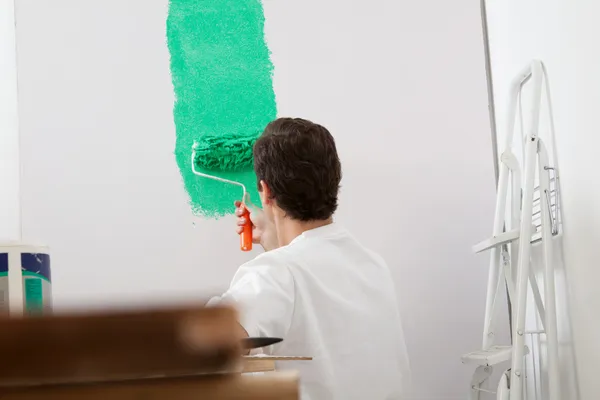 Uomo che dipinge il muro con un rullo — Foto Stock