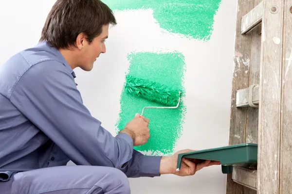 Hombre maduro pintando la pared con un rodillo — Foto de Stock