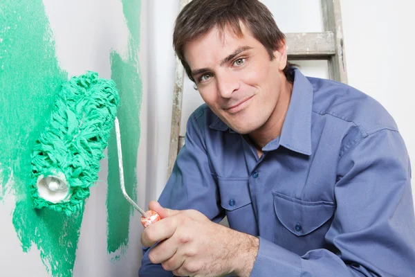 Homem maduro pintando a parede com um rolo — Fotografia de Stock