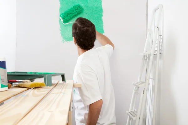 Homem pintando a parede com rolo — Fotografia de Stock