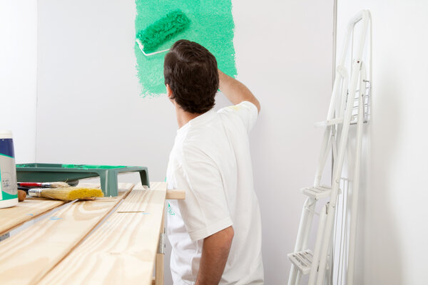 Человек краски стены с роликом

