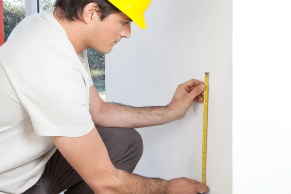 Young contractor measuring wall — Stock Photo, Image