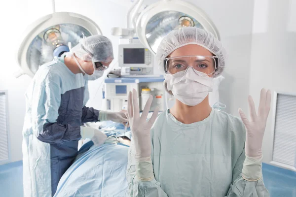 Vrouwelijke chirurg vragen voor handschoenen Stockfoto