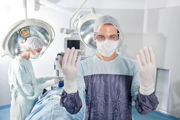 Mężczyzna chirurg z prośbą o rękawice — Zdjęcie stockowe