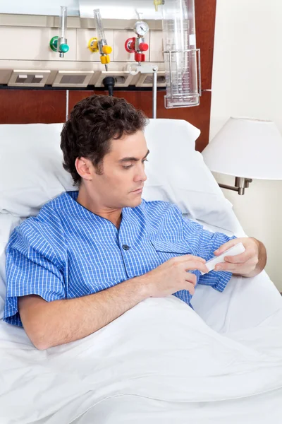 Paciente sentado na cama lendo caixa de remédio — Fotografia de Stock