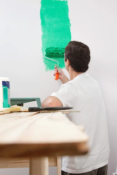 Мужчина рисует дом с роликом — стоковое фото