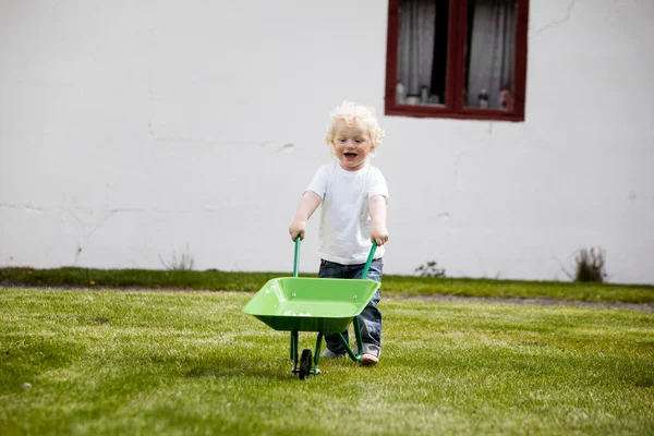 Jovem criança empurrando carrinho de mão — Fotografia de Stock