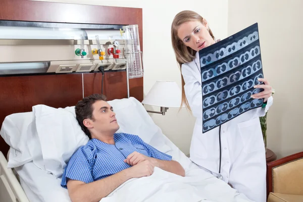 Doctor and patient examining X-ray report — Stock Photo, Image
