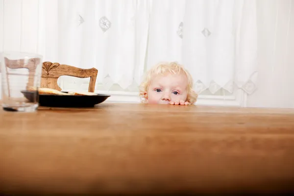Criança espreitando a mesa — Fotografia de Stock