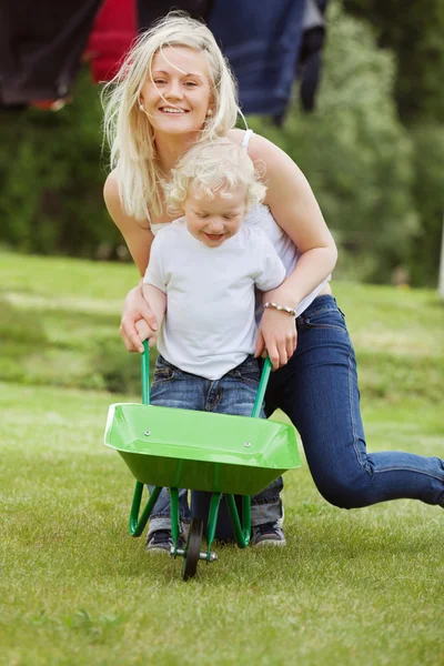 Madre e figlio spingendo una carriola — Foto Stock