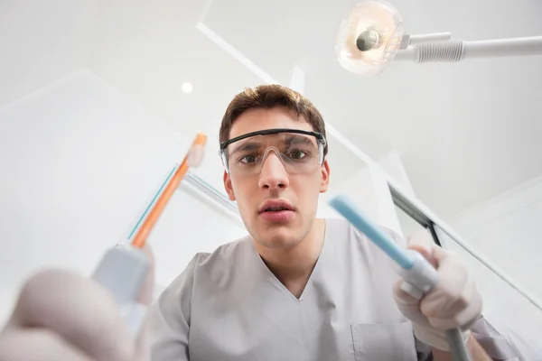 Junger Mann hält Zahnwerkzeug in der Hand — Stockfoto