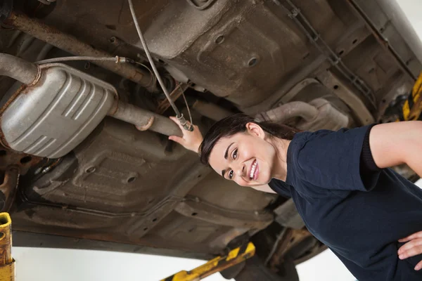 Glimlachend vrouwelijke mechanic onder auto — Stockfoto