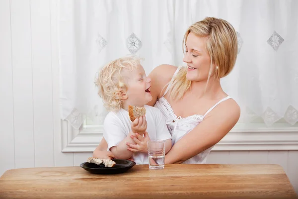 Mãe olhando para menino comendo pão — Fotografia de Stock