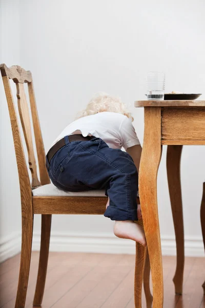 Ребенок пытается слезть со стула — стоковое фото