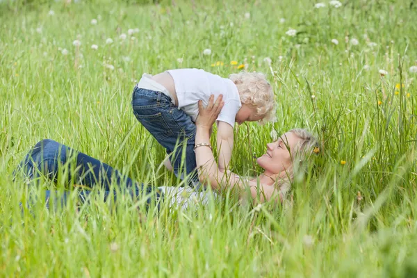 Moeder liggen op gras en het spelen met zoon — Stockfoto