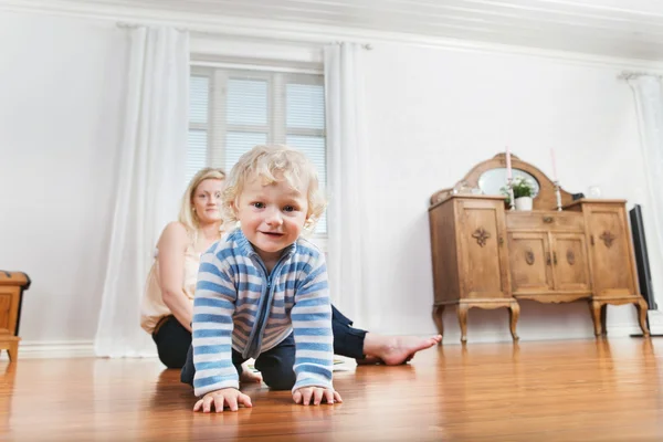 Bambino strisciare con madre in background — Foto Stock