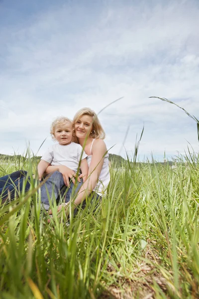 아들과 함께 풀밭에 앉아 어머니 — 스톡 사진