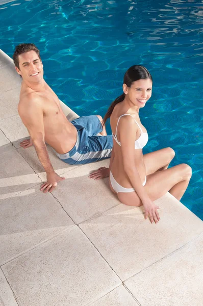 Uśmiechnięta para siedzi w pobliżu basenu — Zdjęcie stockowe