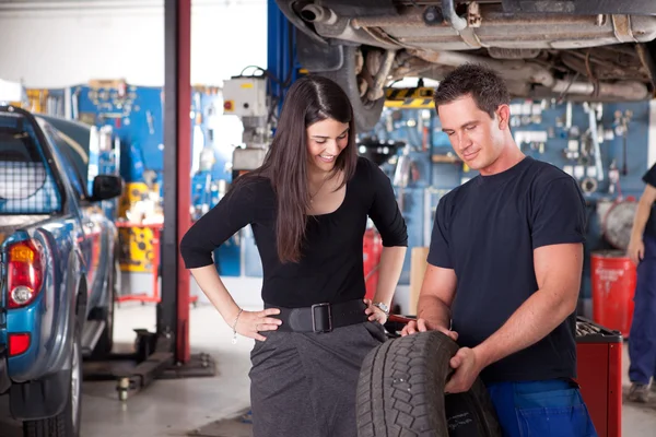 Mecánico mostrando neumático a mujer cliente —  Fotos de Stock