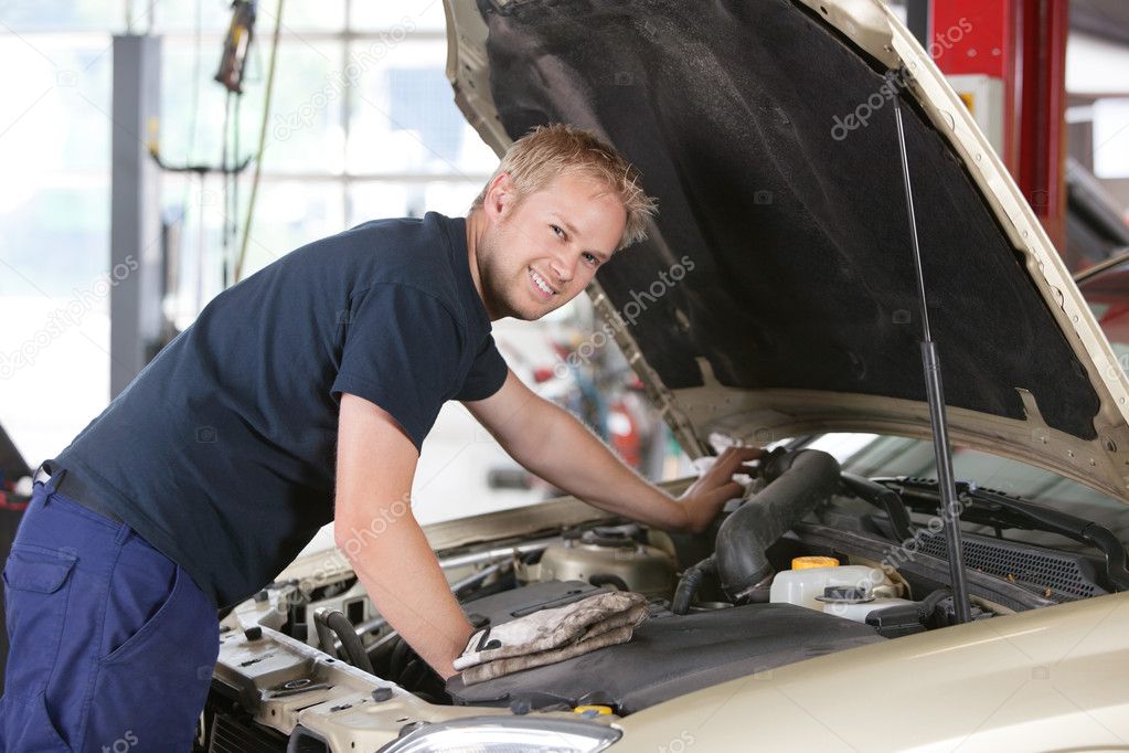 Smiling mechanic working on car