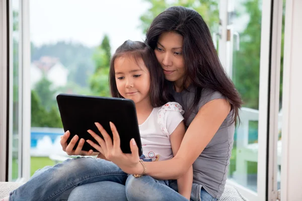 Мать и девочка с электронной книгой — стоковое фото