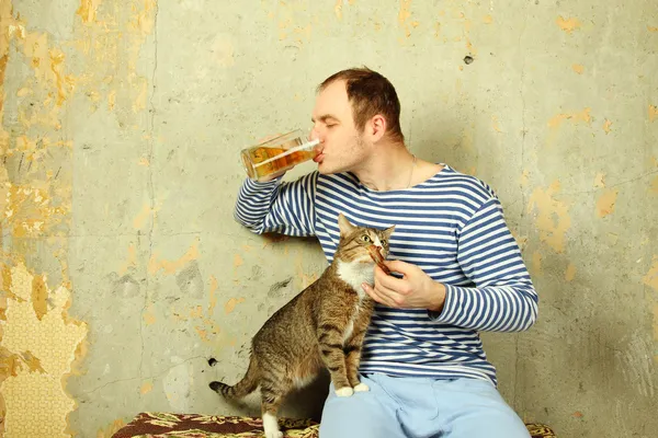 Men with a beer next to the cat steals fish — Stock Photo, Image