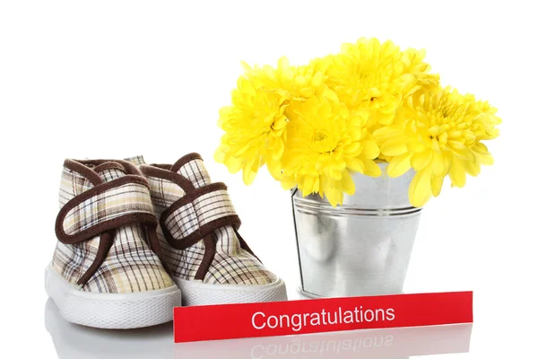 Sapatos infantis perto de um balde com flores — Fotografia de Stock