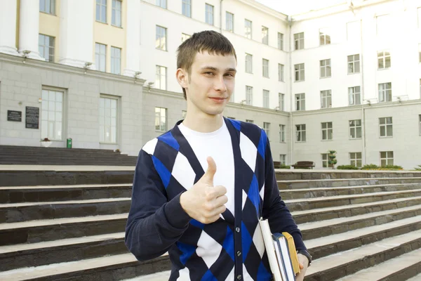 Mužský student na koleji s učebnicemi. palec nahoru — Stock fotografie