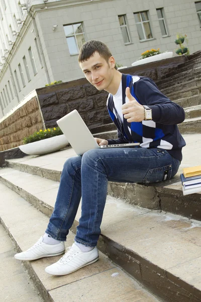 Mladý student pracuje na notebooku. palec nahoru — Stock fotografie