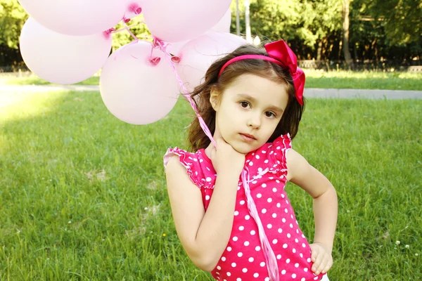 Menina no parque com balões cor de rosa — Fotografia de Stock