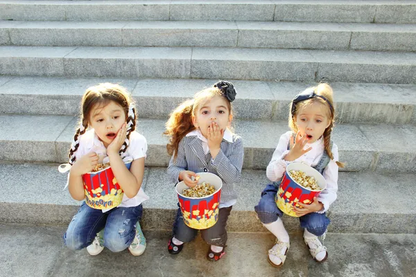 Üç küçük kız arkadaş patlamış mısır yemek — Stok fotoğraf